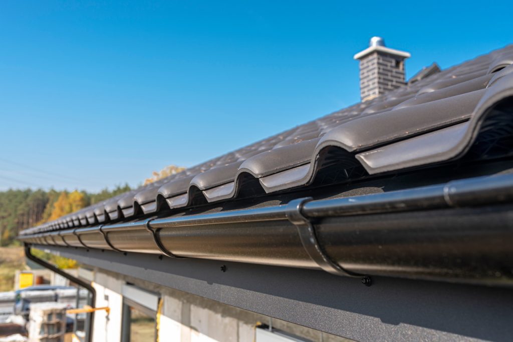 dark gray tiled roof with a black gutter
